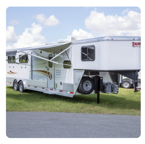 A horse trailer is parked on the side of the road