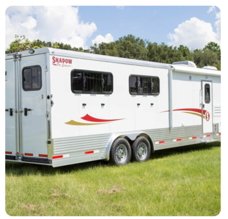 A shadow horse trailer is parked in a grassy field