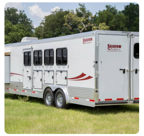 A shadow trailer is parked in a grassy field