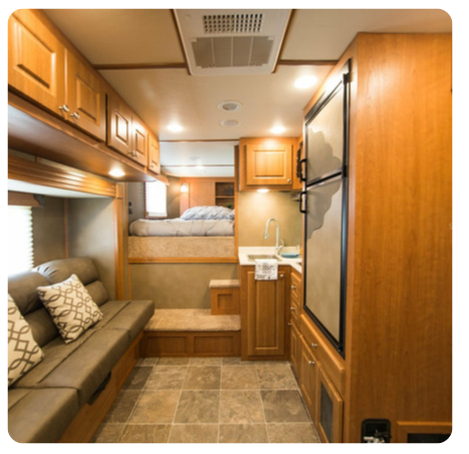 The inside of a rv with a couch and a refrigerator
