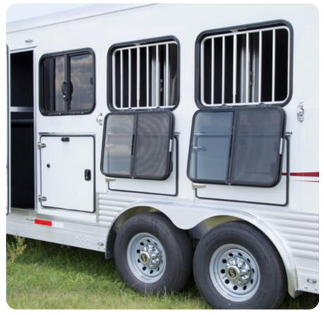 A white trailer with bars on the windows is parked in the grass