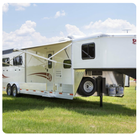 A horse trailer is parked in a grassy field