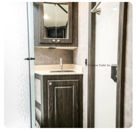 A bathroom in a trailer with a sink and mirror