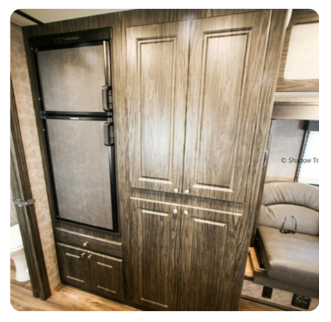 A rv with wooden cabinets and a refrigerator