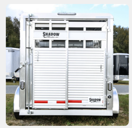 A shadow trailer is parked in a grassy field.