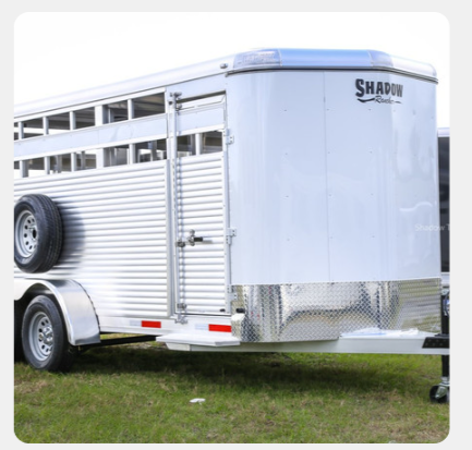 A shadow horse trailer is parked in the grass