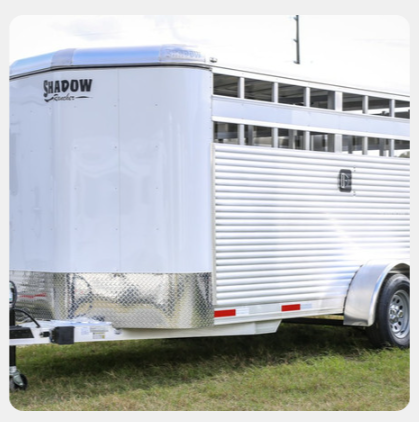 A shadow trailer is parked in the grass