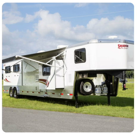 A shadow trailer is parked in a grassy field