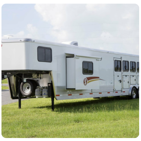 A horse trailer is parked in a grassy field