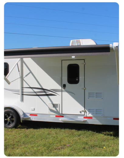 A white trailer is parked in a grassy field