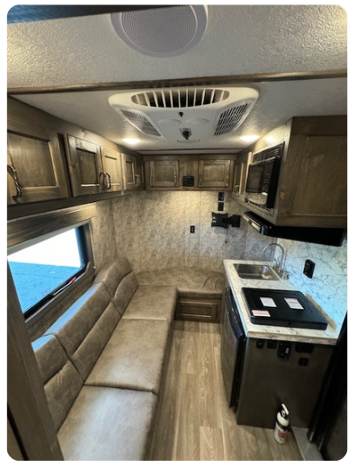 The inside of a camper with a couch and a kitchen.