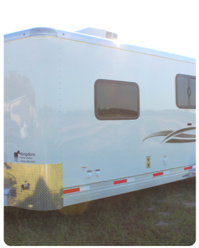 A white trailer is parked in a grassy field