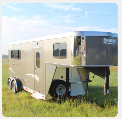 A shapin horse trailer is parked in a grassy field