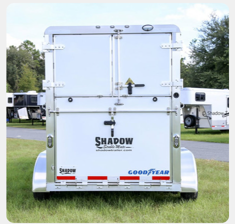 A shadow trailer is parked in a grassy field