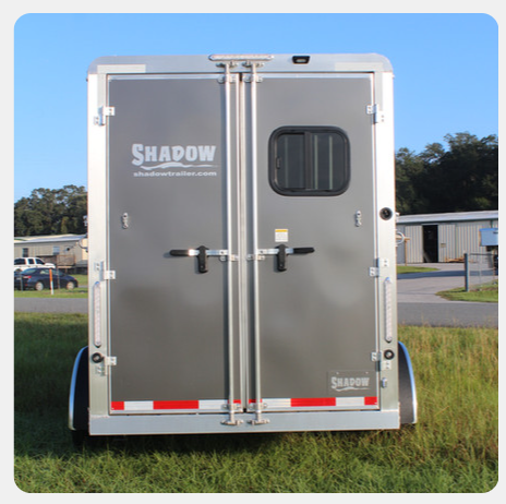 A shadow trailer is parked in a grassy field.