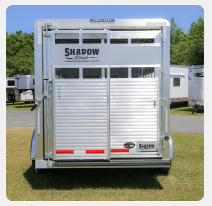 A shadow trailer is parked in a grassy field