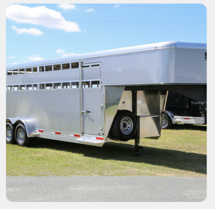 A horse trailer is parked in a grassy field