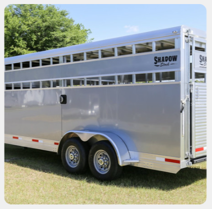 A shadow horse trailer is parked in the grass