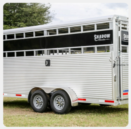 A shadow horse trailer is parked in the grass