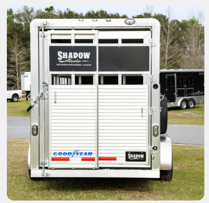 A shadow trailer is parked in a grassy area