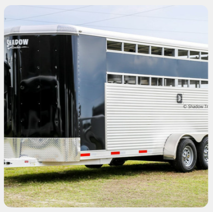 A shadow horse trailer is parked in the grass
