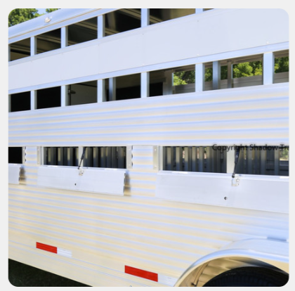 A white horse trailer with a red and white stripe on the side