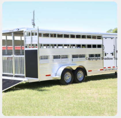 A horse trailer is parked in a grassy field ..