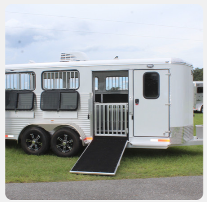A white horse trailer with a ramp on the side