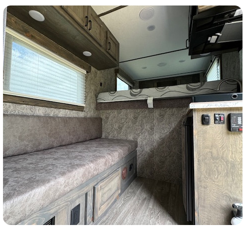 The inside of a camper with a couch and a bed.