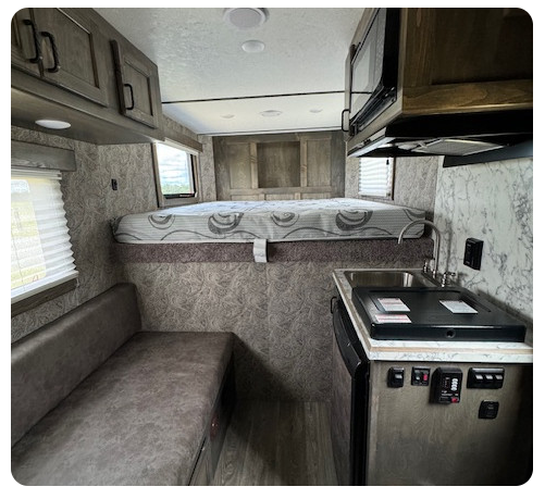 The inside of a camper with a bed and a kitchen.