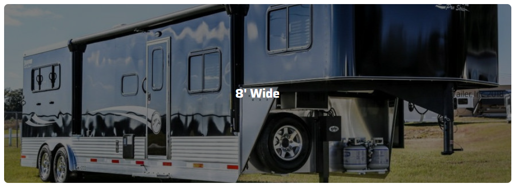 A large trailer is parked in a grassy field.