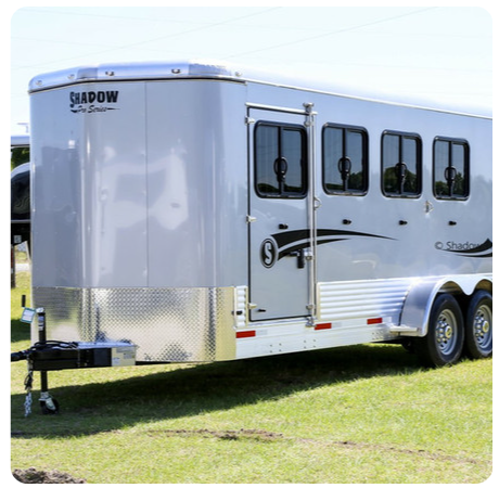 A shadow horse trailer is parked in the grass