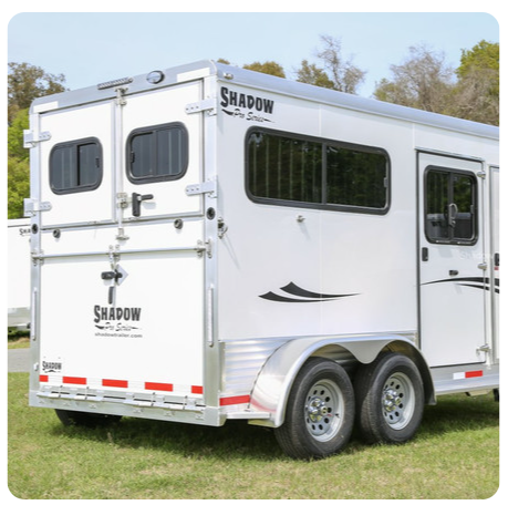 A shadow horse trailer is parked in a grassy field.