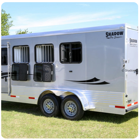 A shadow horse trailer is parked in the grass