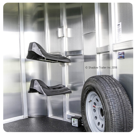 A horse trailer with saddle racks and a tire.