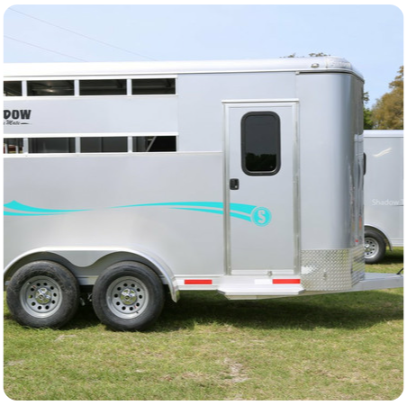 A horse trailer is parked in a grassy field.