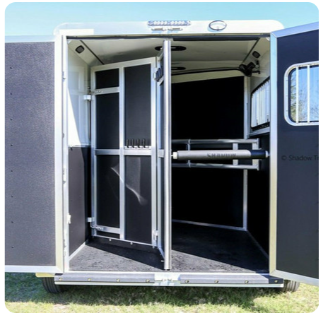 The inside of a horse trailer with the doors open