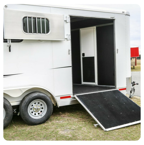 A white horse trailer with the door open and a ramp.