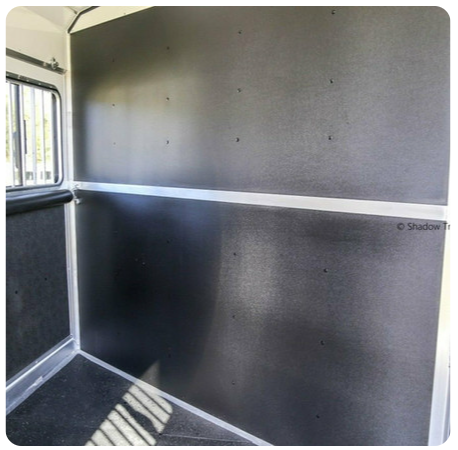 The inside of a horse trailer with a black wall and a window.
