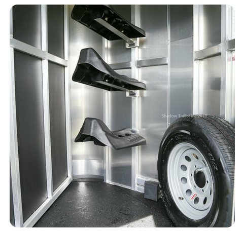 The inside of a trailer with saddle racks and a tire