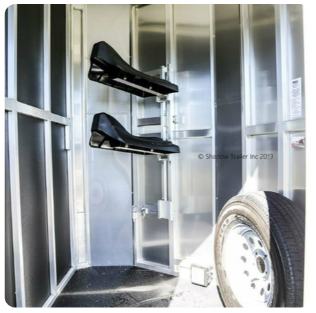 A horse trailer with two saddle racks and a tire
