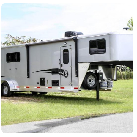 A horse trailer is parked on the side of the road