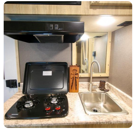 A kitchen with a stove top oven and a sink
