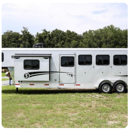 A white horse trailer with the letter s on the side