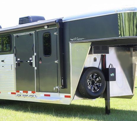 A horse trailer is parked in a grassy field.
