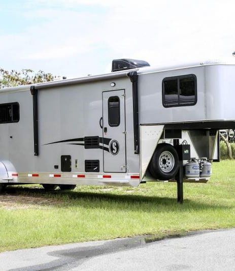 A horse trailer is parked on the side of the road.