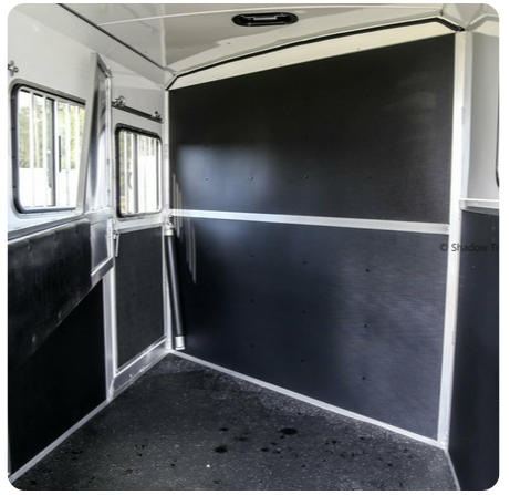 The inside of a horse trailer with black walls and windows