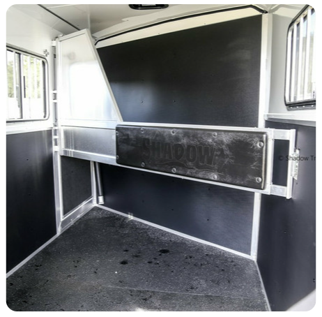 The inside of a horse trailer with a sign that says shadow on it.