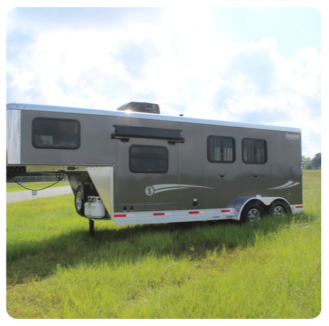 A horse trailer is parked in a grassy field