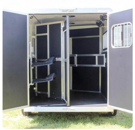 The inside of a horse trailer with the doors open.
